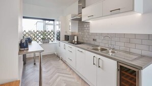 A modern kitchen with white cabinets, a stainless steel sink, and a built-in wine cooler. - Host & Stay | Apartment 2, High Street (Caernarfon)