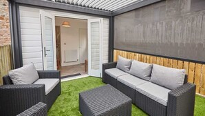 A patio area with wicker furniture, a wooden fence, and a view into the house. - Host & Stay | Apartment 2, High Street (Caernarfon)