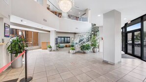 A spacious lobby with a high ceiling, a chandelier, multiple staircases, and potted plants. - Best Layout/Relaxing OceanfrontSuite (Myrtle Beach)