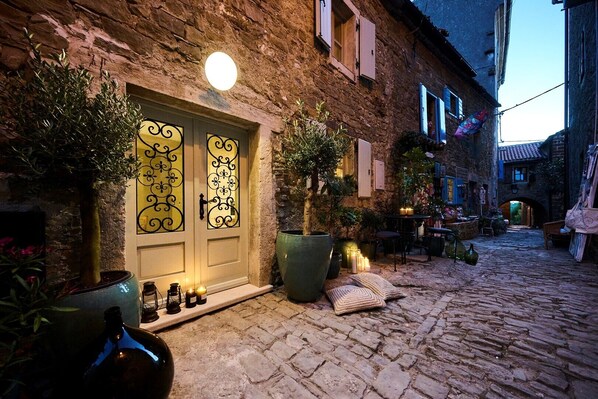 A stone building with a decorative door, potted plants, and outdoor seating.