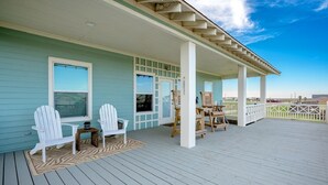 Eine überdachte Veranda mit Adirondack-Stühlen und einem kleinen Tisch, mit Blick auf eine reizvolle Landschaft.