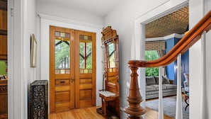 A wooden staircase with a handrail leading to a living room with a gray sofa and a patterned rug. - Breathtaking Harwich Retreat w/ Heated Pool and Spa RPAM086 (Harwich)