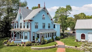 A large, light blue house with a steep gable roof, a front porch, and a stone pathway leading to the entrance. - Breathtaking Harwich Retreat w/ Heated Pool and Spa RPAM086 (Harwich)