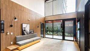 A modern reception area with a wooden wall, a bench, a framed artwork, and a fire extinguisher. - Charlie Sabiá Moema (São Paulo)