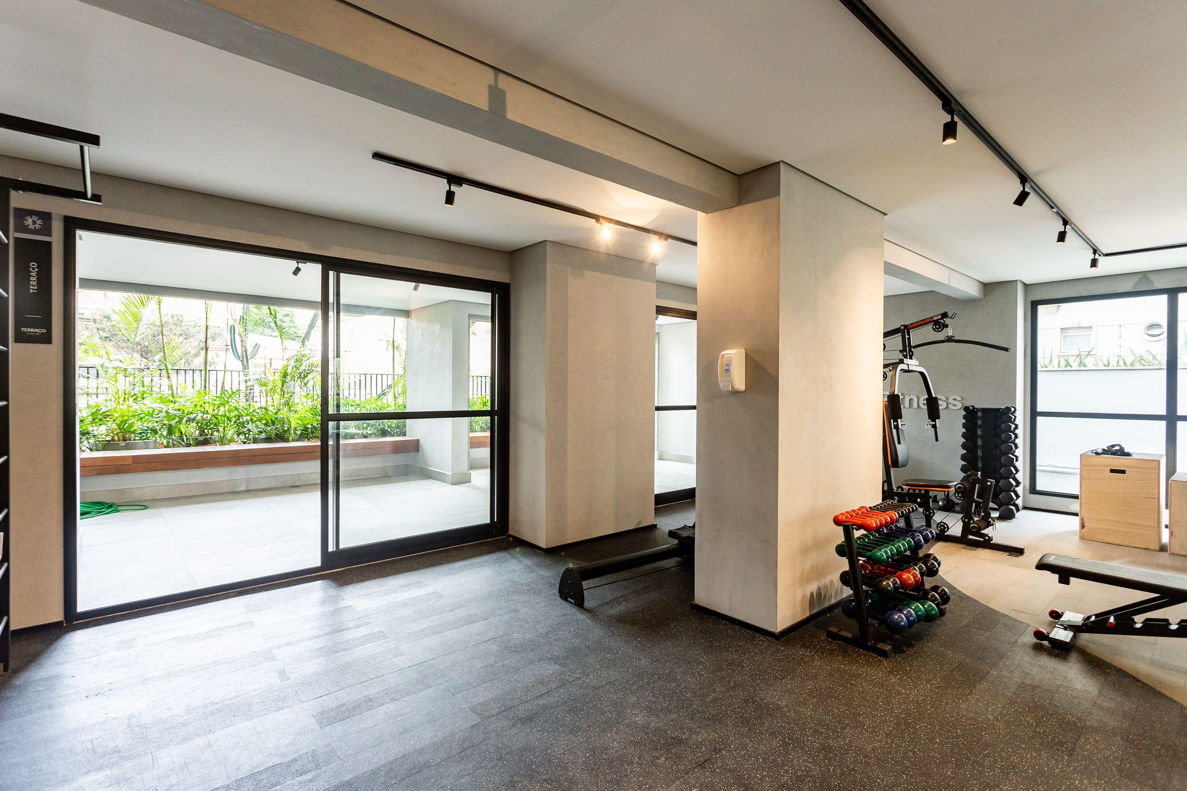 A gym with a weight rack, exercise equipment, and a large window with a view of greenery.
