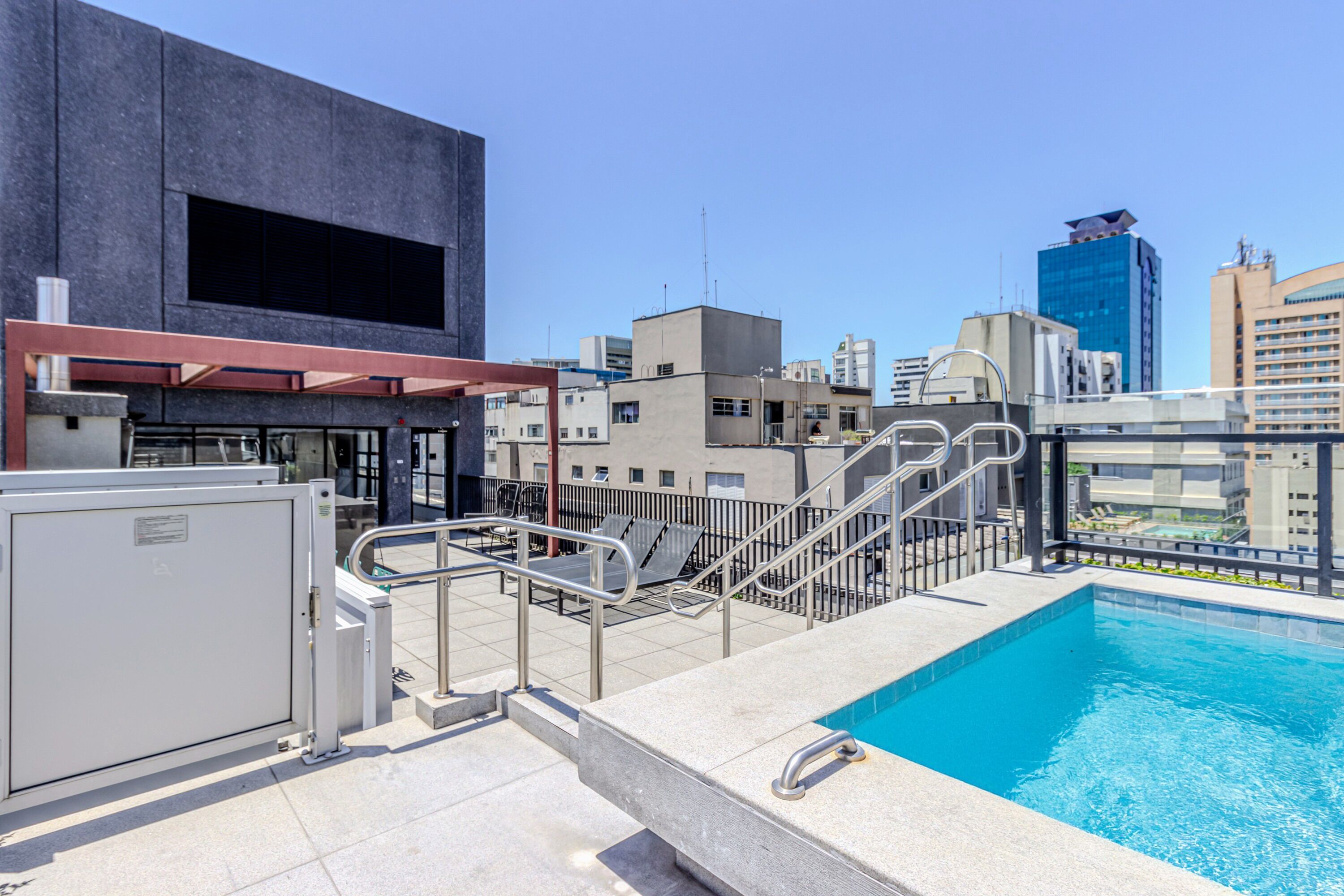 Ein Pool auf dem Dach mit Blick auf die Stadt, ein modernes Gebäude mit einem großen Fenster und einem Metallgeländer.