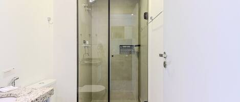 A modern bathroom with a glass-enclosed shower, a white toilet, and a marble sink.