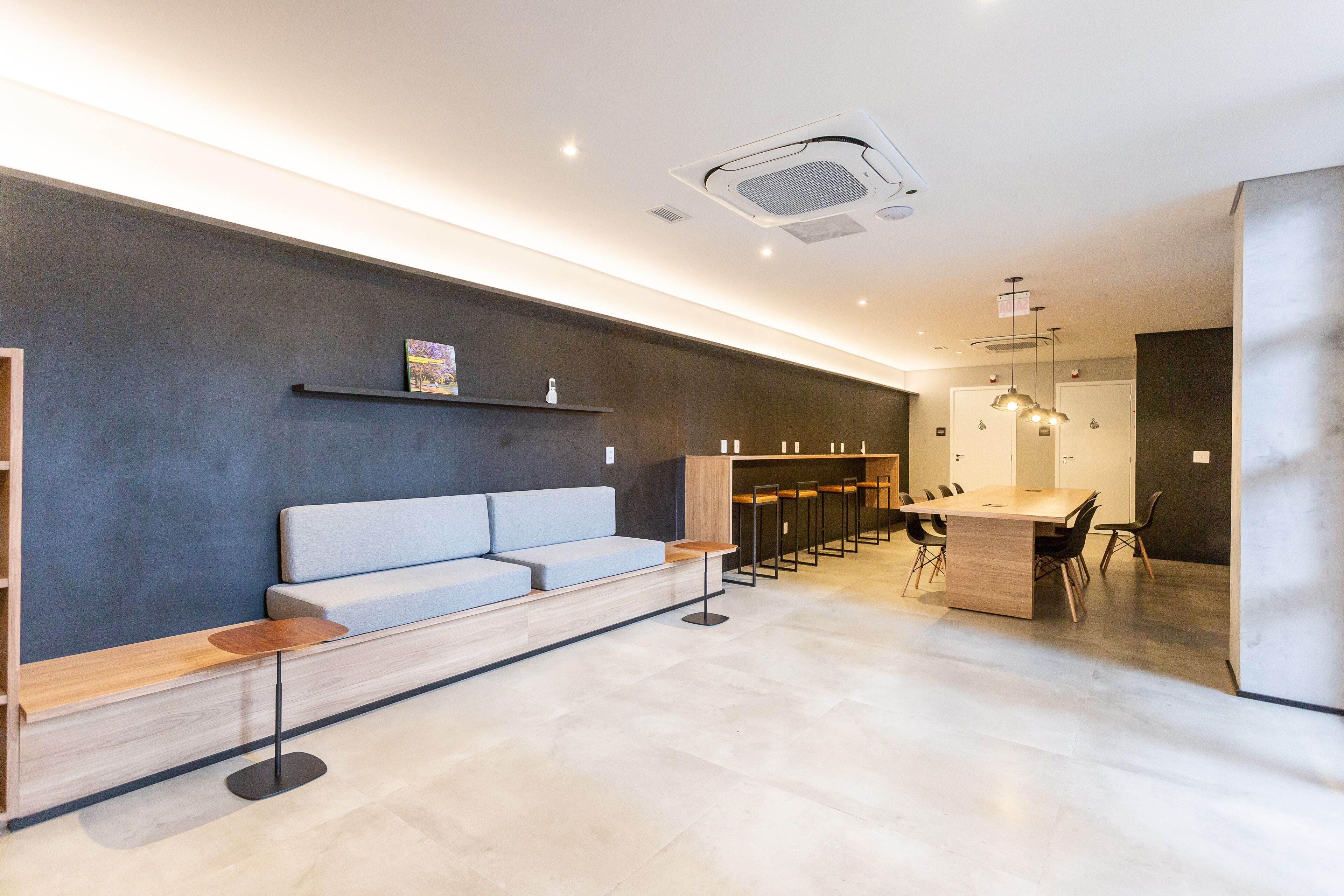 A modern reception area with a sofa, a small table, a bar area, and a seating arrangement.