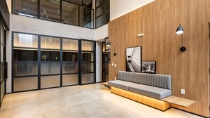 A modern interior with a wooden accent wall, a built-in bench, and a large window with blinds. - Charlie Sabiá Moema (São Paulo)