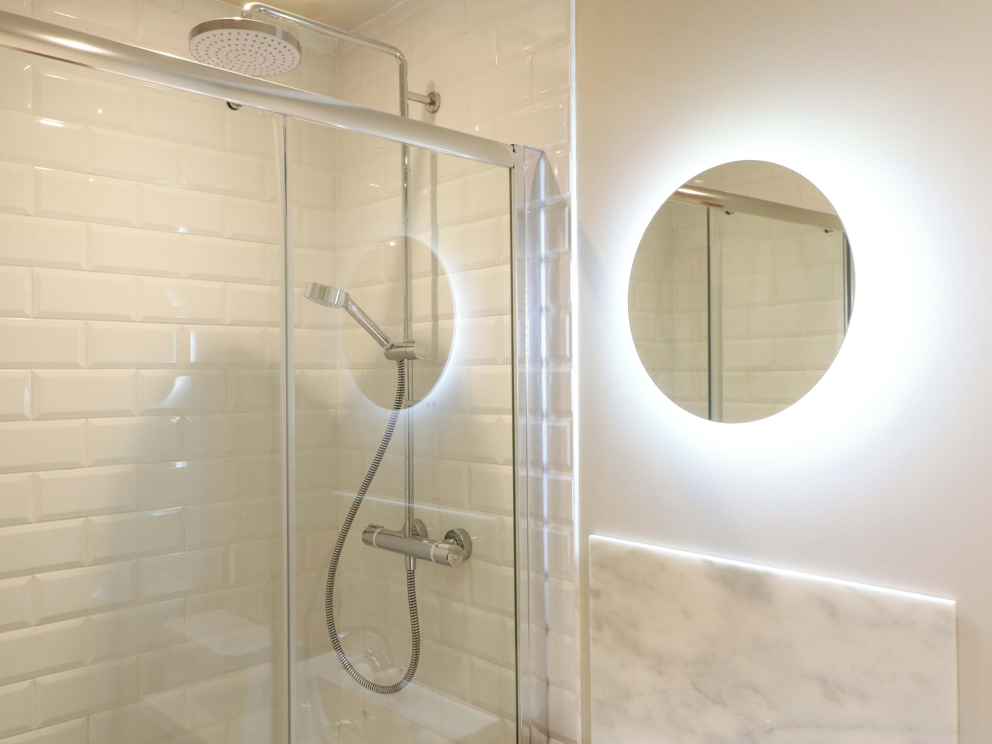 Eine begehbare Dusche mit Duschbrause und Handbrause.