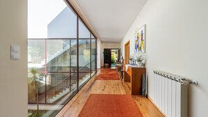 Een moderne hal met een houten vloer, glazen wanden en een rode loopmat die naar een trap leidt.