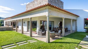 Een modern huis met een stenen gevel, een overdekt terras met tuinmeubilair en een verzorgd gazon.