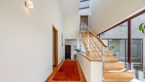 Een modern interieur met een houten trap, een rood tapijt en een groot raam.