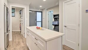 A modern kitchen with white cabinetry, a central island, and a refrigerator. - Fully Renovated Ocean Front Condo at Sea Colony (Sussex County)