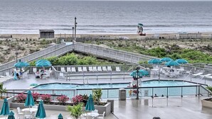 A rooftop pool area with multiple pools, lounge chairs, and umbrellas. - Fully Renovated Ocean Front Condo at Sea Colony (Sussex County)