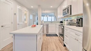 A modern kitchen with white cabinets, stainless steel appliances, and a central island. - Fully Renovated Ocean Front Condo at Sea Colony (Sussex County)