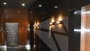 Un vestíbulo moderno con piso reflectante, una mesa de recepción y un panel informativo en la pared.