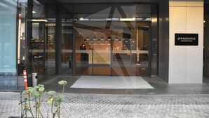 Una entrada moderna de edificio con puertas de cristal, un cartel que dice 'primeistanbul residences' y un pavimento adoquinado.