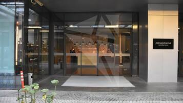 A modern building entrance with glass doors, a sign for 'primeistanbul residences', and a tiled pavement.