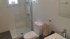 A bathroom with a glass-enclosed shower, a toilet, a sink, and a towel rack. - Phaedrus Living City Flat Demetra 102 (Larnaca)