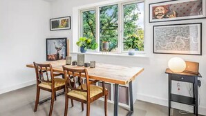 Un'area pranzo con un tavolo e sedie in legno, opere d'arte appese alle pareti e una finestra vista su spazi verdi.