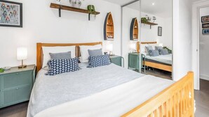 Una camera da letto moderna con un letto grande, comodini, uno specchio e un comodino verde.