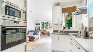 Una cucina moderna con elettrodomestici integrati, una zona pranzo con divano e ampie finestre che si affacciano sul verde.