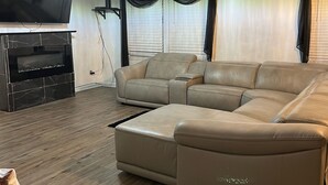 A living room with a sectional sofa, a flat-screen TV, a fireplace, and a ceiling fan. - Home away from home. Relaxing and welcoming stay.  20min from Myrtle Beach. (Conway)