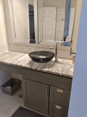 A bathroom with a marble countertop, a black vessel sink, a mirror, and a door. - Home away from home. Relaxing and welcoming stay.  20min from Myrtle Beach. (Conway)