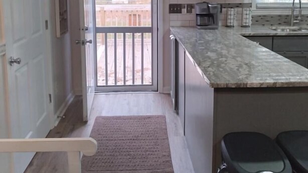 A compact kitchen with a built-in island, a window with blinds, and a door leading outside. - Home away from home. Relaxing and welcoming stay.  20min from Myrtle Beach. (Conway)