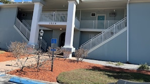 A building with a two-story structure, a balcony on the second floor, and a staircase on the first floor. - Coastal Waters Cozy Studio unit 102 (New Smyrna Beach)