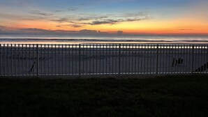 A beach view with a metal fence in the foreground. - Coastal Waters Cozy Studio unit 102 (New Smyrna Beach)