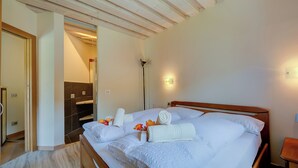 Habitación de hotel con cama de madera, ropa de cama blanca y baño con espejo y toallero.