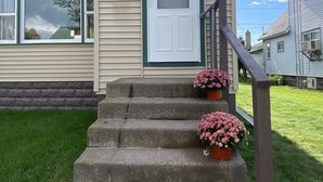 A beige house with a white door and green trim, number 612, with a small porch and steps leading up to the entrance. - Beautiful Home in Ontonagon - 2 blocks from Lake Superior (Ontonagon)