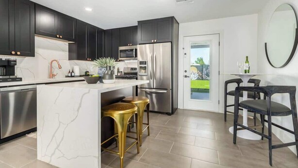 A modern kitchen with dark cabinets, stainless steel appliances, and a marble island with stools. - Scottsdale Retreat | Pool, Putt & More (Scottsdale)
