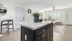 A modern kitchen with a central island, dark cabinetry, and a white countertop. - Scottsdale Retreat | Pool, Putt & More (Scottsdale)