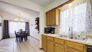 Una cocina con armarios de madera, un lavabo y una zona de comedor con una mesa y sillas.