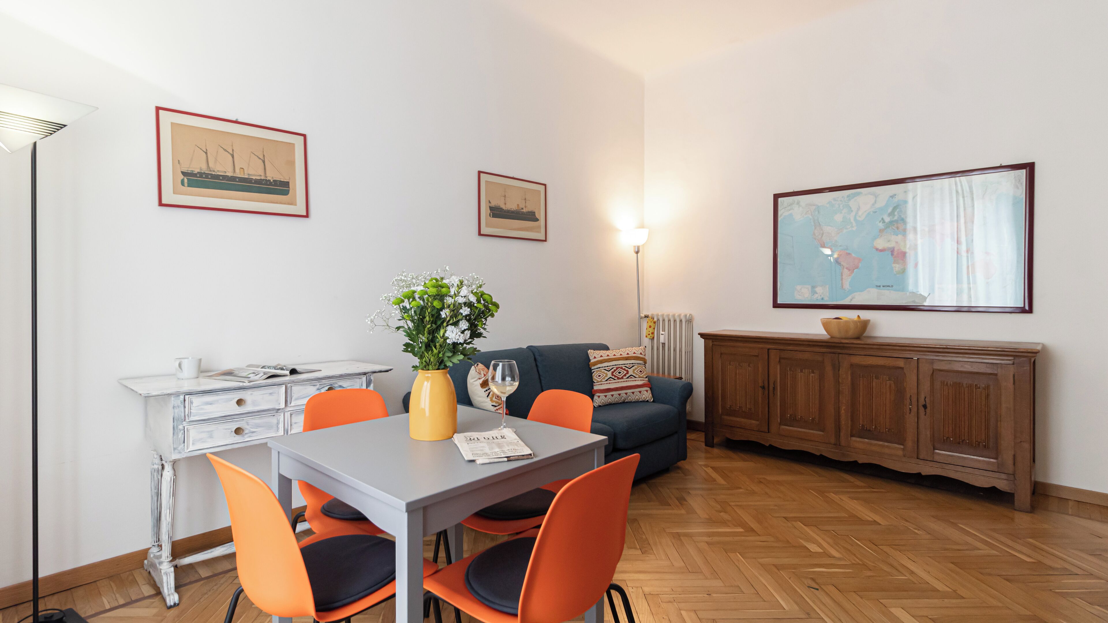 Un coin repas comprenant une table, des chaises, un vase avec des fleurs, un globe terrestre et un meuble.
