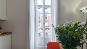 Une pièce avec une porte blanche, une chaise rouge et un vase de fleurs.