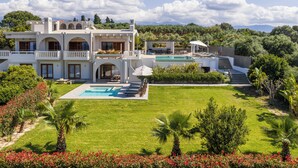 Ein großes Haus mit Swimmingpool, mehreren Balkonen und einem gepflegten Garten.