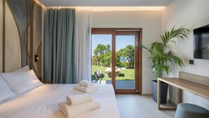 Ein Hotelzimmer mit Bett, Fernseher, Schreibtisch, Pflanze und Blick ins Freie.