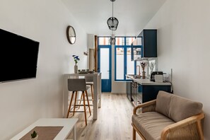 Cocina compacta con comedor, sofá y televisor.