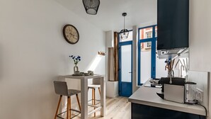 Eine moderne Küche mit Essbereich, einer Wanduhr und einer blauen Tür, die nach draußen führt.