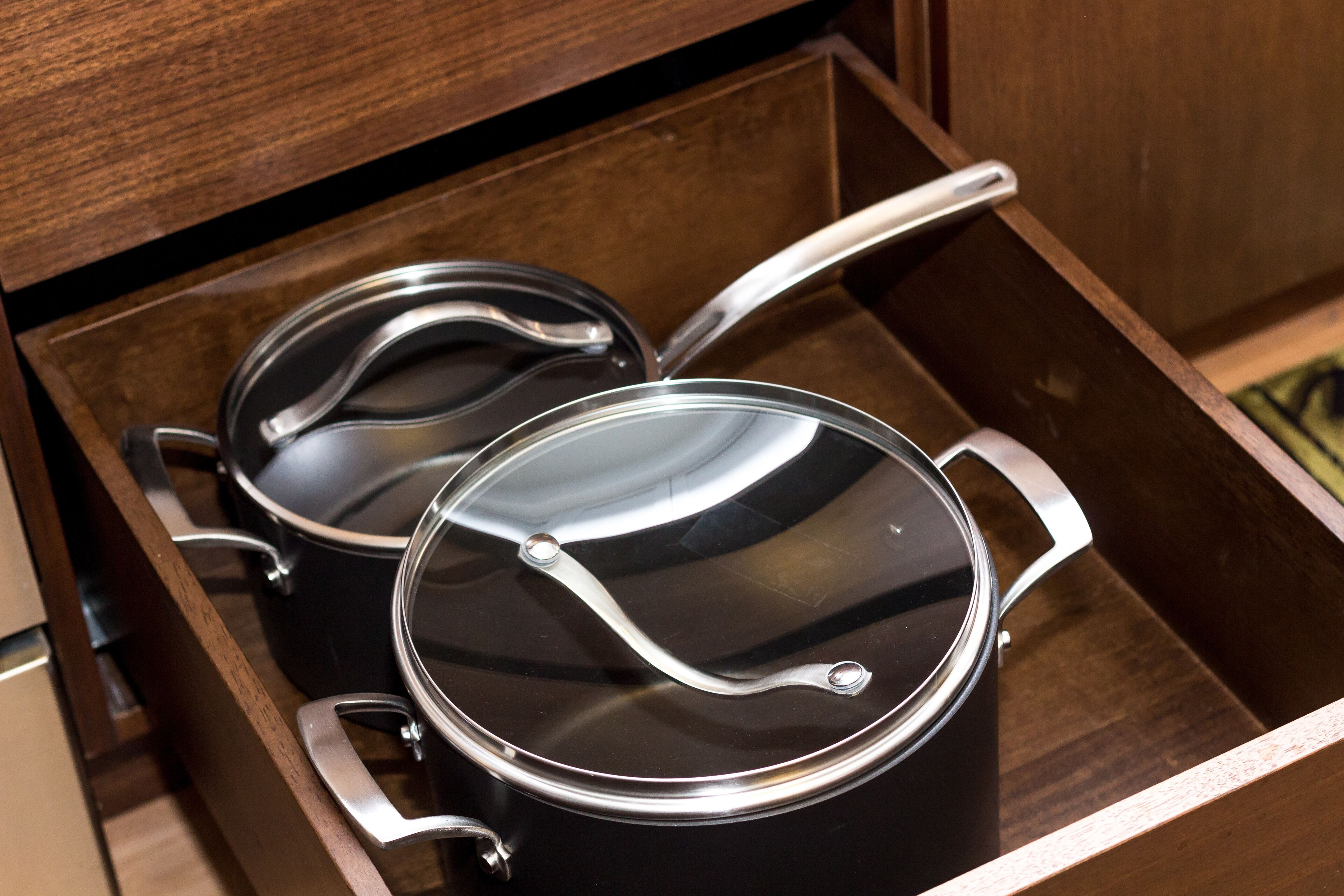 A drawer with two black pots with lids.
