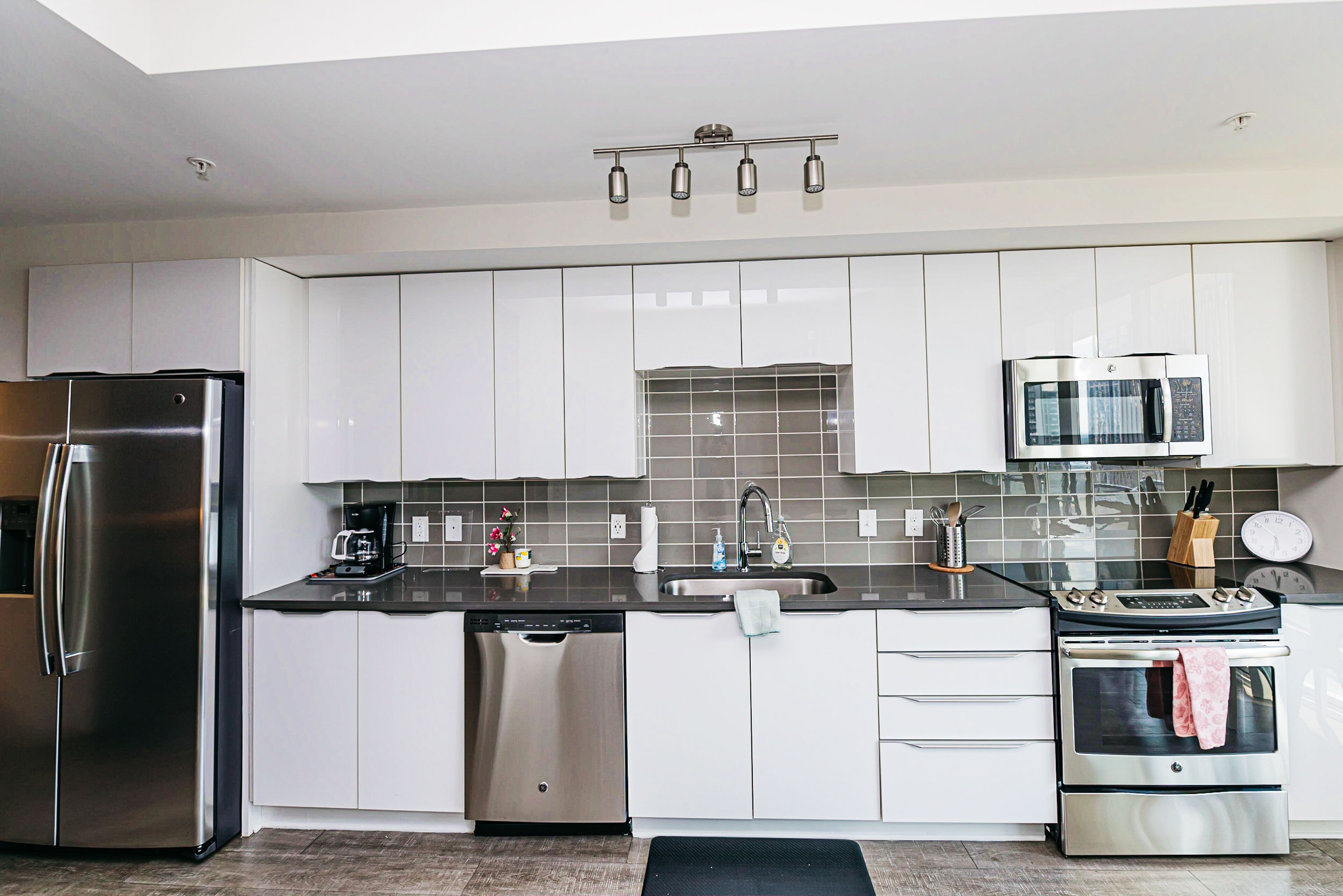 A modern kitchen with stainless steel appliances, white cabinets, and a black countertop.