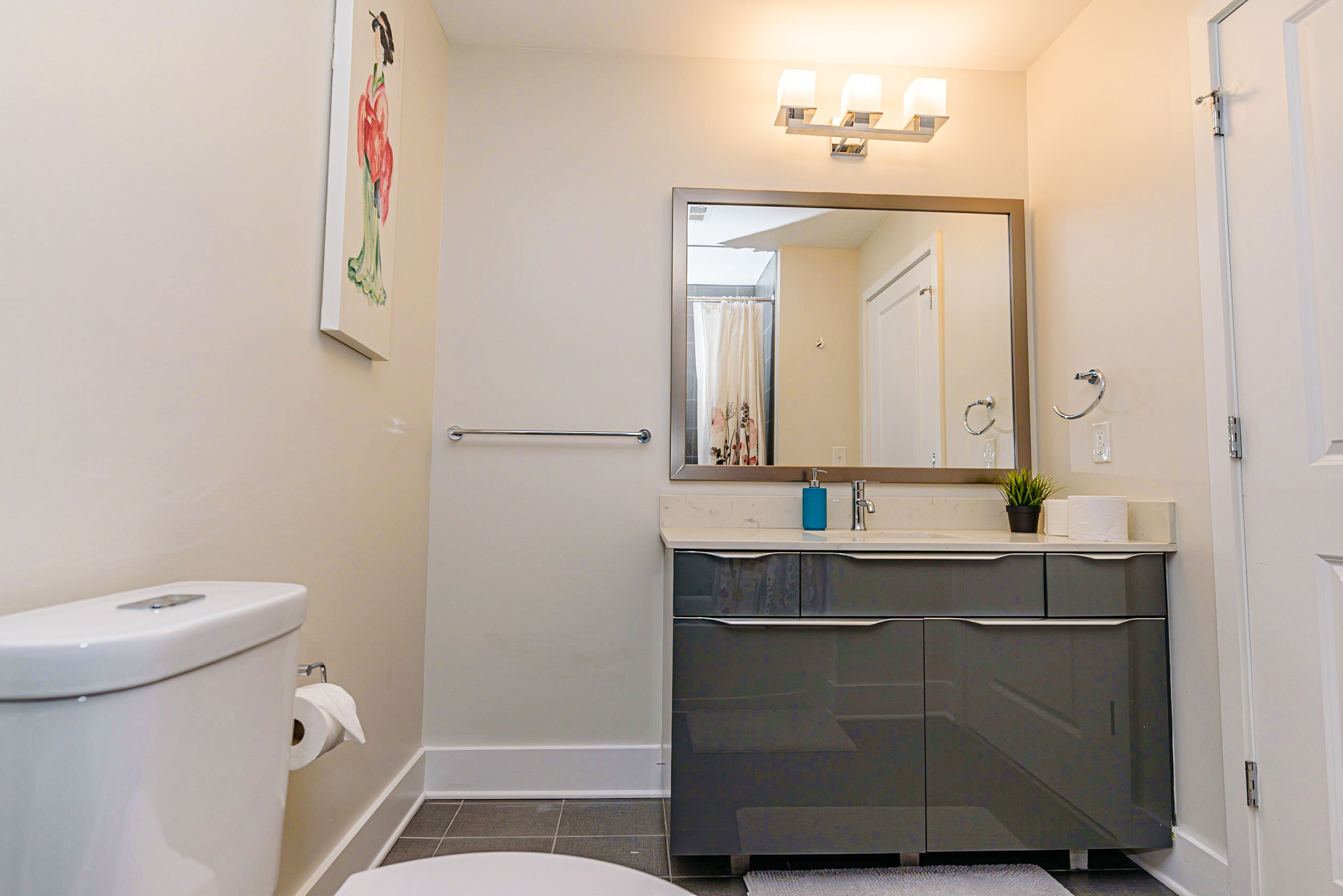 A bathroom with a toilet, sink, mirror, and towel rack.