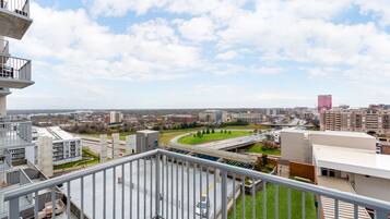 Un immeuble de grande hauteur doté d’un balcon donnant sur un paysage urbain, avec des routes et d’autres bâtiments visibles.