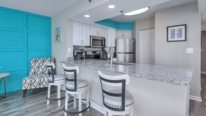 A kitchen with white cabinets, stainless steel appliances, and a turquoise accent wall.