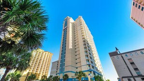A tall hotel with multiple floors, a prominent entrance, and a view of the ocean.