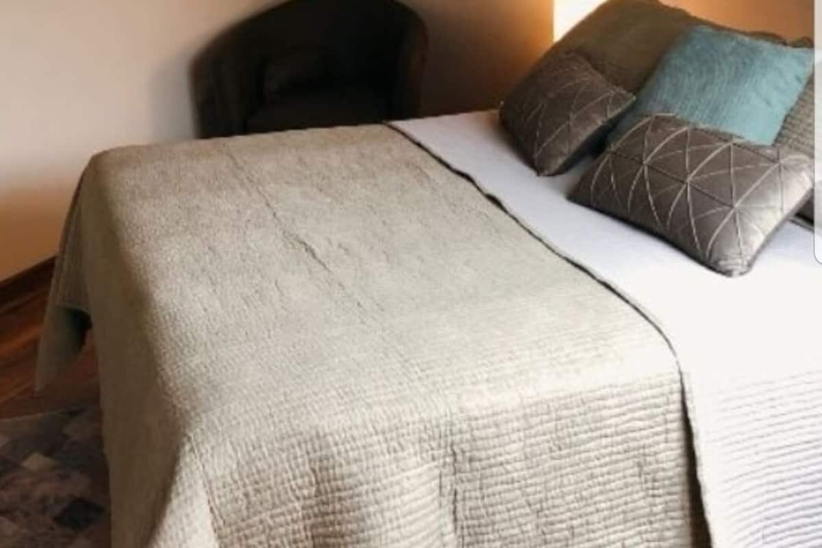 A bedroom with a bed, a chair, and a wall-mounted lamp.